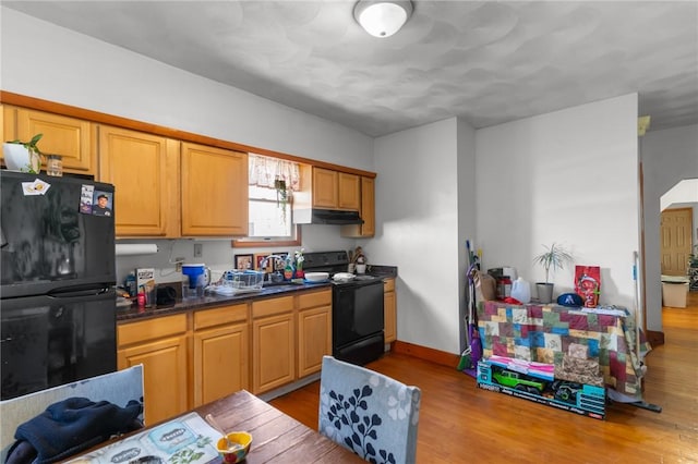 kitchen with black appliances, sink, and light hardwood / wood-style flooring