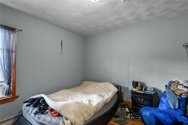 bedroom featuring baseboard heating and hardwood / wood-style floors