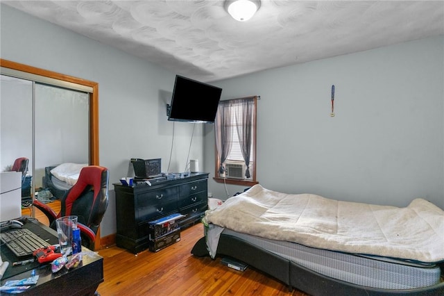 bedroom with light wood-type flooring, a closet, and cooling unit