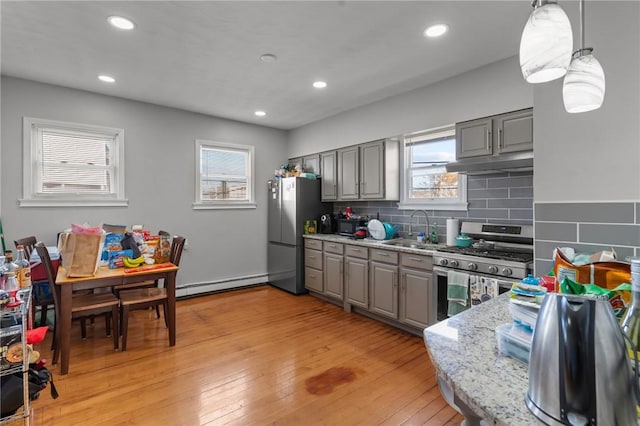 kitchen featuring decorative light fixtures, a baseboard heating unit, gray cabinets, sink, and stainless steel appliances