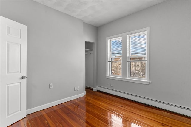 spare room with baseboard heating and wood-type flooring