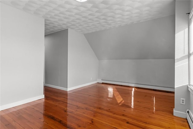 additional living space featuring a baseboard radiator, wood-type flooring, lofted ceiling, and a wealth of natural light