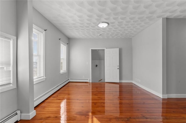 unfurnished room featuring baseboard heating and wood-type flooring