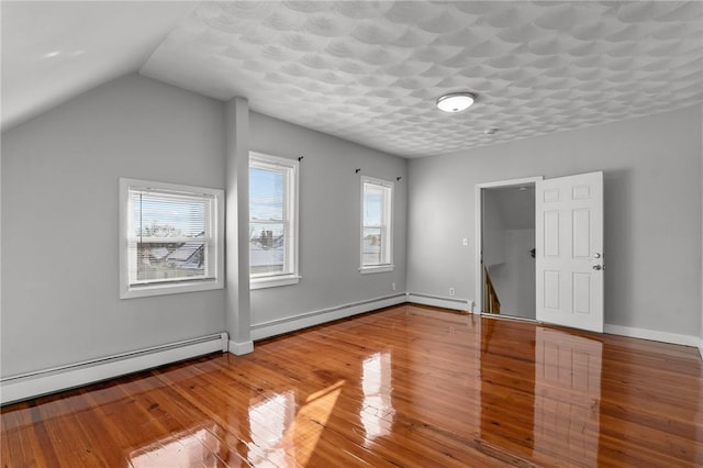 additional living space featuring lofted ceiling, baseboard heating, and hardwood / wood-style flooring