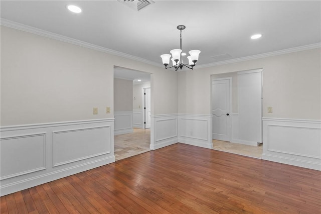 spare room with an inviting chandelier, crown molding, and wood-type flooring