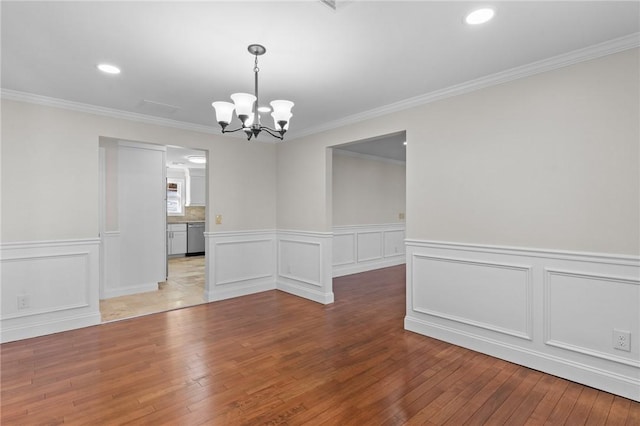 unfurnished dining area with a chandelier, crown molding, and hardwood / wood-style flooring