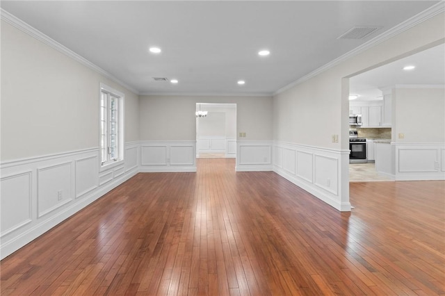 empty room featuring a chandelier, ornamental molding, and light hardwood / wood-style flooring