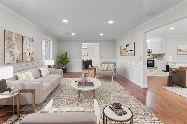 living room with light hardwood / wood-style flooring, crown molding, and an inviting chandelier