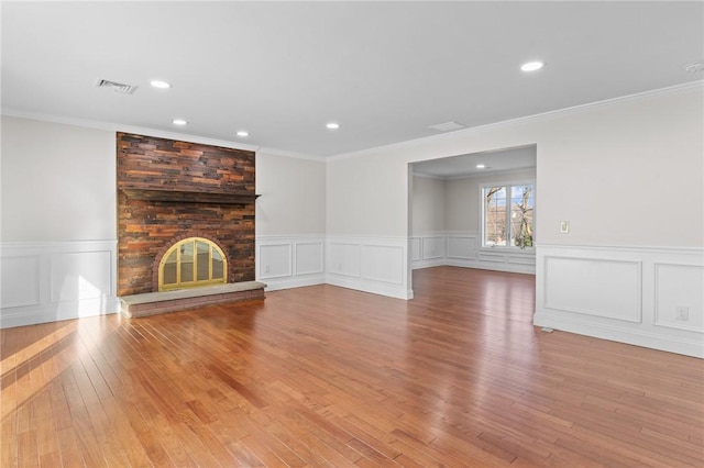 unfurnished living room featuring light wood-type flooring, a fireplace, and crown molding