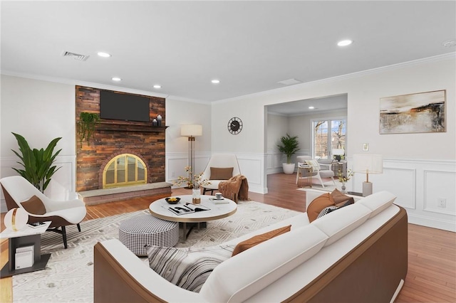 living room featuring a brick fireplace, crown molding, and light hardwood / wood-style flooring