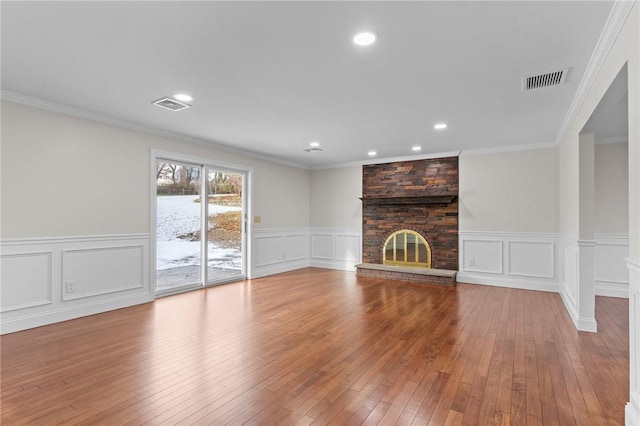 unfurnished living room with a brick fireplace, ornamental molding, and light hardwood / wood-style flooring