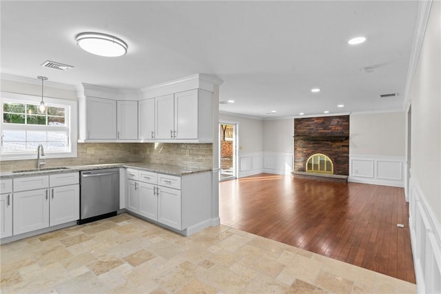 kitchen featuring sink, white cabinetry, stainless steel dishwasher, and a fireplace