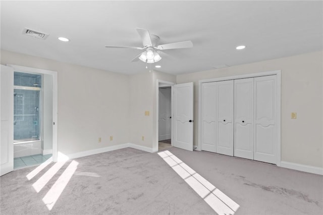 unfurnished bedroom with ceiling fan, light colored carpet, a closet, and ensuite bath