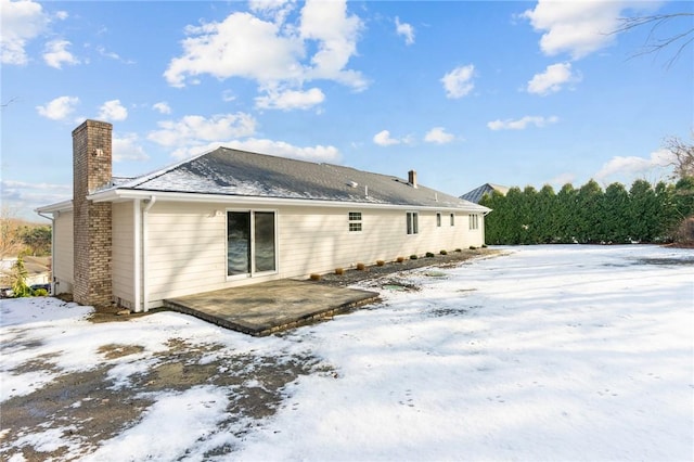 snow covered house featuring a patio