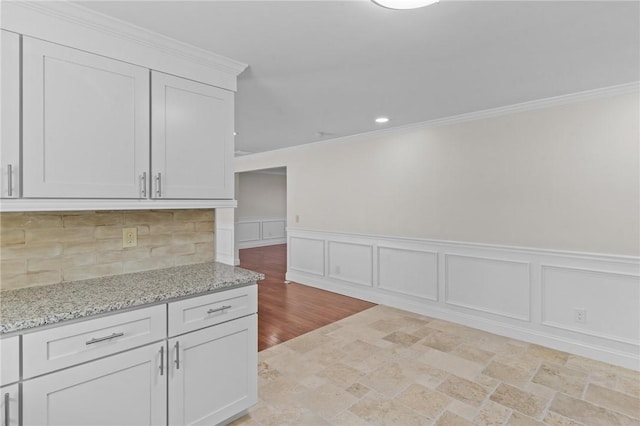 kitchen with white cabinets, light stone countertops, and crown molding