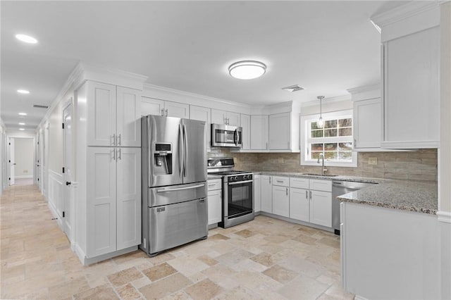 kitchen featuring white cabinetry, appliances with stainless steel finishes, hanging light fixtures, light stone counters, and sink