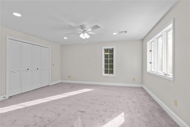 unfurnished bedroom featuring ceiling fan, light carpet, and a closet