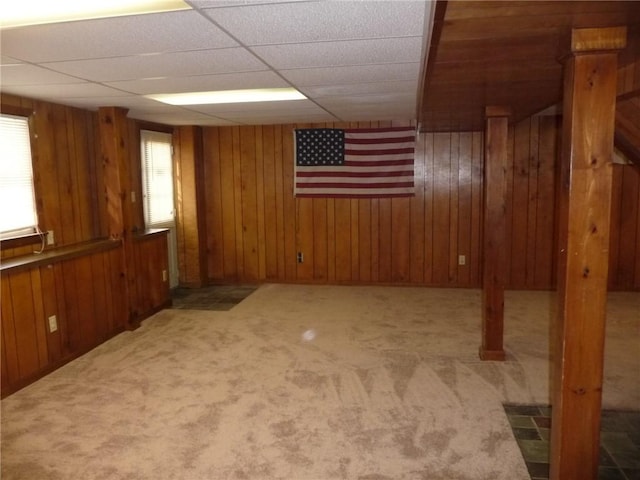 basement featuring light carpet and wooden walls