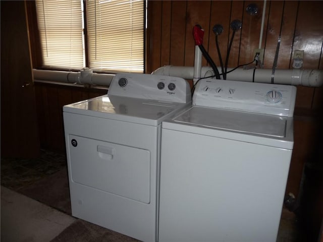 laundry area featuring wood walls and washer and clothes dryer