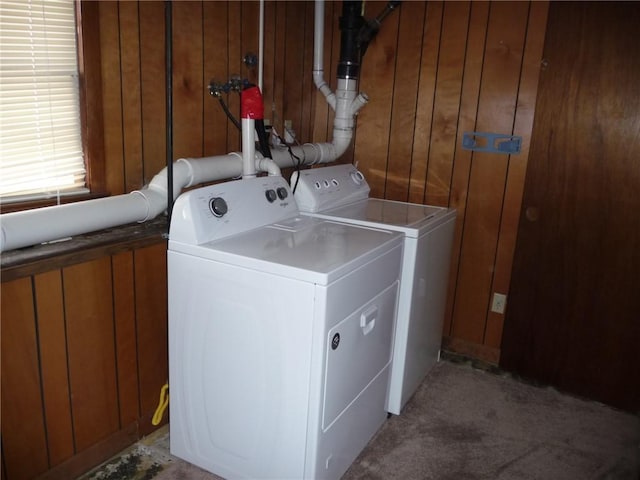 laundry room with washer and dryer, light carpet, and wood walls