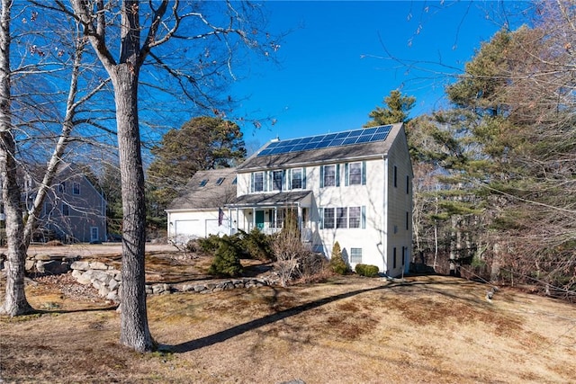 colonial inspired home featuring a garage and solar panels