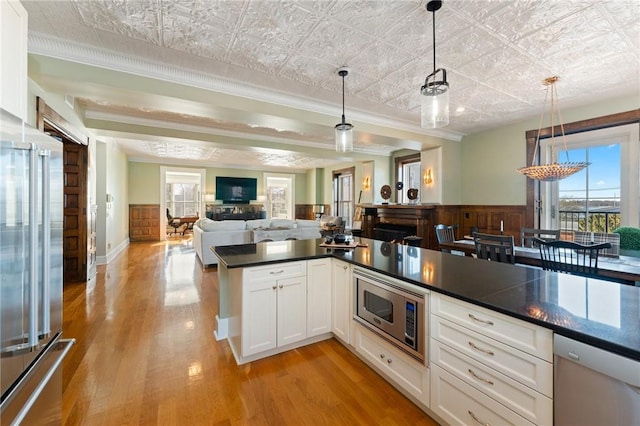 kitchen with white cabinets, decorative light fixtures, and appliances with stainless steel finishes