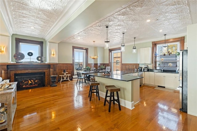 kitchen with decorative light fixtures, white cabinetry, crown molding, and a breakfast bar area