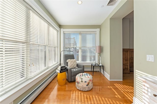 living area with hardwood / wood-style flooring and a baseboard heating unit