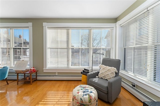 living area featuring wood-type flooring, baseboard heating, and a wealth of natural light