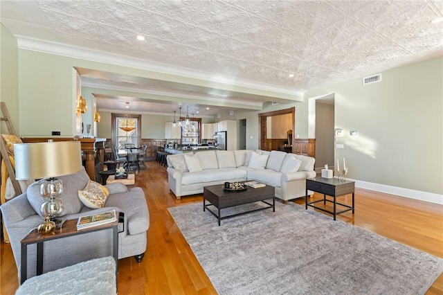 living room with wood-type flooring, an inviting chandelier, and crown molding