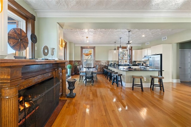 interior space with a kitchen bar, decorative light fixtures, white cabinetry, and crown molding