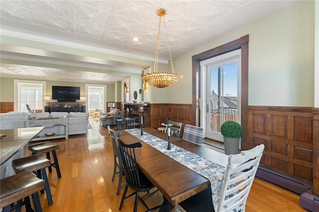 dining area featuring a baseboard radiator, ornamental molding, plenty of natural light, and light wood-type flooring