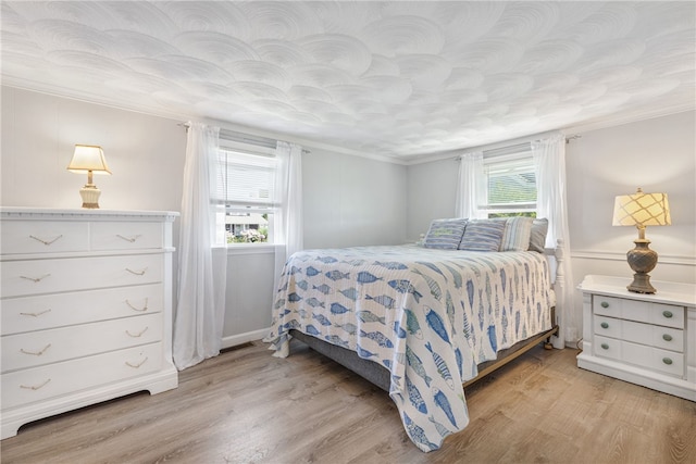 bedroom with light wood-type flooring and ornamental molding