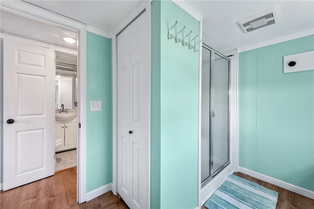 bathroom with wood-type flooring, crown molding, a shower with shower door, and vanity