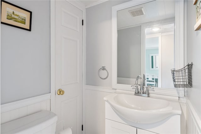 bathroom featuring toilet, vanity, and crown molding