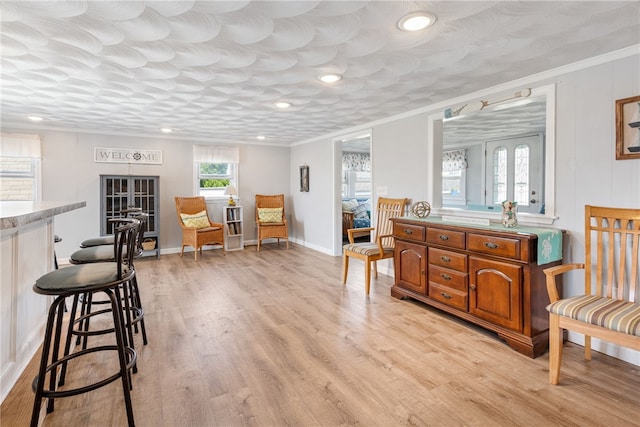 sitting room with ornamental molding and light wood-type flooring