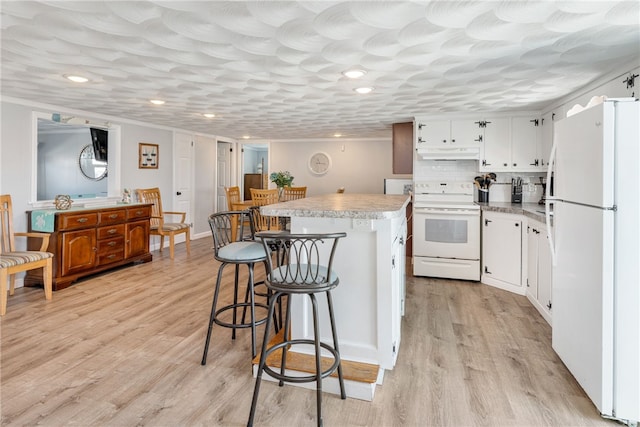 kitchen featuring white appliances, white cabinets, a kitchen island, decorative backsplash, and light hardwood / wood-style floors