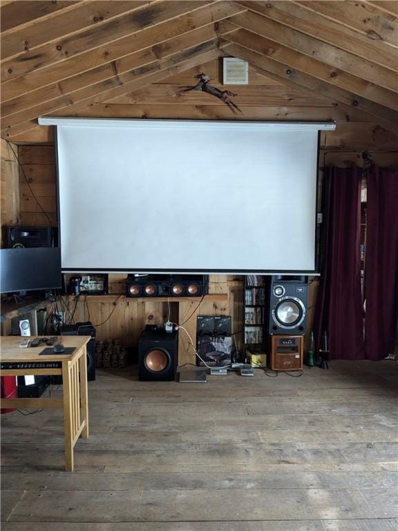 home theater featuring vaulted ceiling, wooden walls, and wood-type flooring