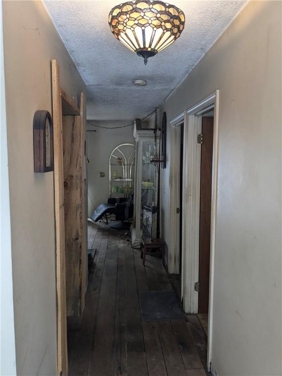 hall featuring a textured ceiling and dark hardwood / wood-style flooring