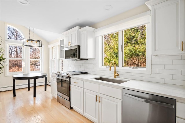 kitchen featuring lofted ceiling, sink, baseboard heating, white cabinetry, and appliances with stainless steel finishes