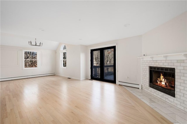 unfurnished living room with lofted ceiling, a fireplace, a baseboard radiator, and light hardwood / wood-style floors