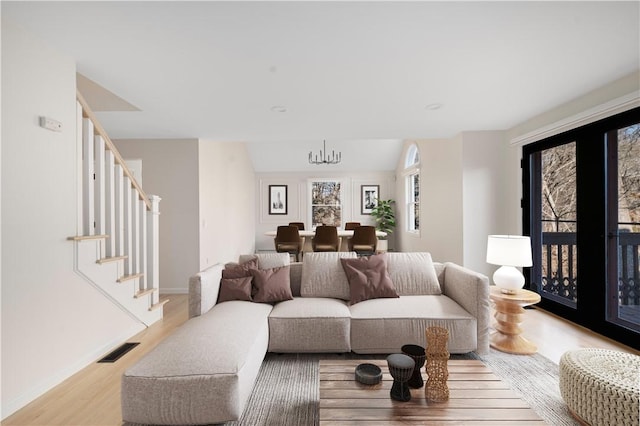 living room featuring vaulted ceiling, a notable chandelier, and light wood-type flooring