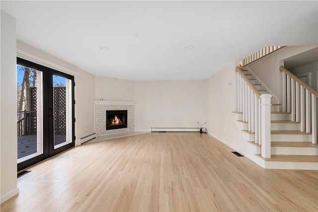 unfurnished living room featuring french doors, baseboard heating, and light hardwood / wood-style floors