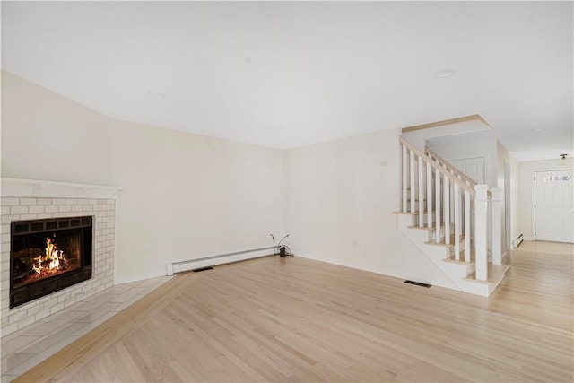 unfurnished living room featuring a baseboard radiator, a brick fireplace, and light hardwood / wood-style flooring