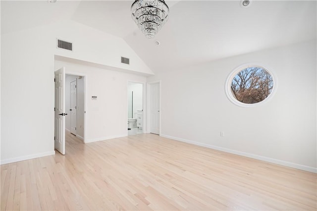 unfurnished room with lofted ceiling, light hardwood / wood-style floors, and a notable chandelier