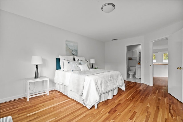 bedroom featuring hardwood / wood-style flooring and connected bathroom