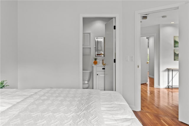 bedroom with ensuite bathroom and light wood-type flooring