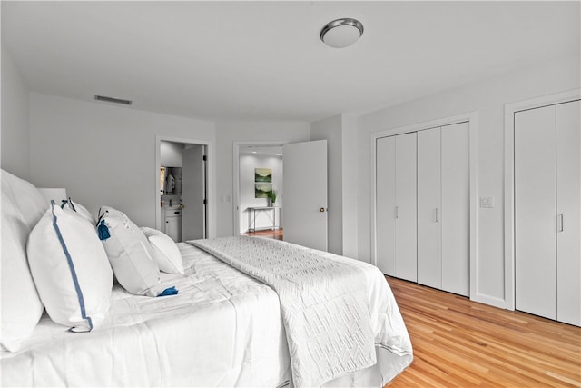 bedroom with multiple closets, hardwood / wood-style flooring, and connected bathroom