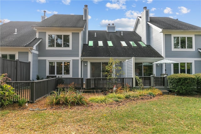 back of property with a wooden deck and a yard