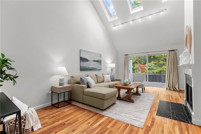 living room featuring a skylight, a high ceiling, and light hardwood / wood-style flooring